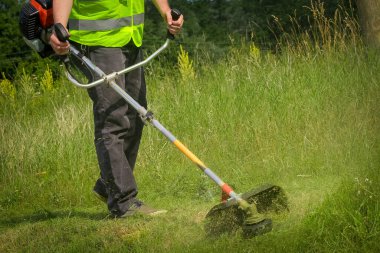 Çim biçme makinesiyle çim biçen işçiler