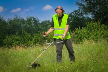 Çim biçme makinesiyle çim biçen işçiler