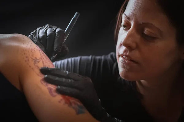 Female tattoo artist making tattoo on a men`s arm