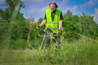 Çim biçme makinesiyle çim biçen işçiler
