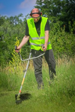 Çim biçme makinesiyle çim biçen işçiler