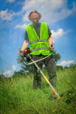 Çim biçme makinesiyle çim biçen işçiler