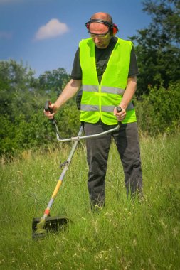 Çim biçme makinesiyle çim biçen işçiler