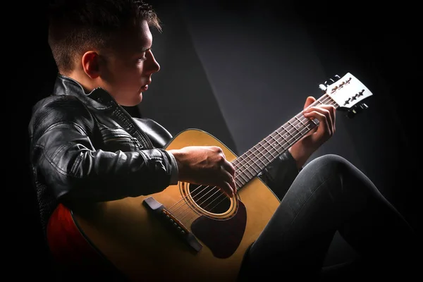 Young men playing the guitar with black background