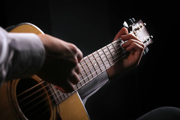 Young men playing the guitar with black background