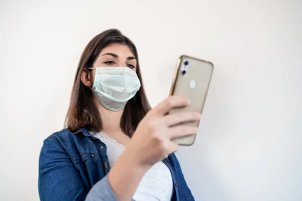 Portrait of woman with medical protection mask using her smartphone.