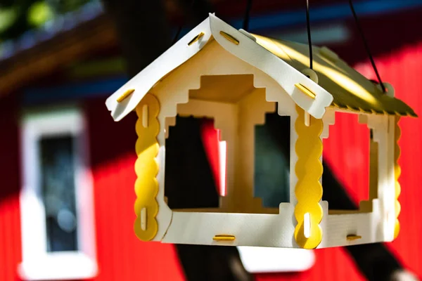 Modern plastic bird feeder and windows on the background