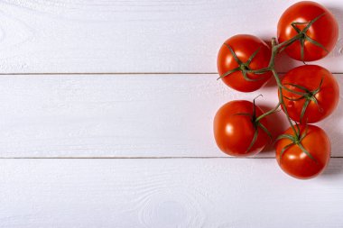 Beyaz ahşap arka planda beş taze domates.