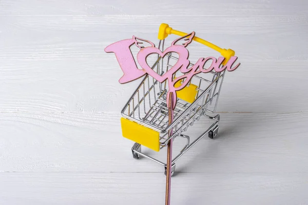 Love sign in shopping cart on a white wooden background
