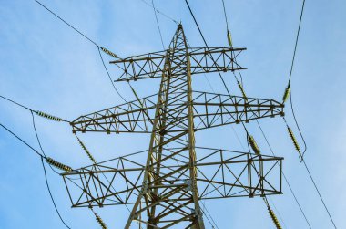 Mavi gökyüzüne karşı yüksek voltajlı elektrik hatları kulesi. - Yakın çekim. Elektrik iletimi.