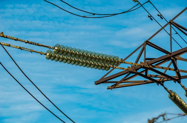 Yüksek voltajlı bir elektrik hattının kulesinin kablolarına izolatörler yakın plan..