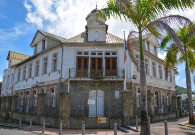 Le Francois, Martinique - 18 Eylül 2018: Hotel de Ville, Belediye Binası - bayrağı ve palmiye ağaçları olan eski bir bina. Mavi gökyüzü. Beyaz bulutlar. Boşluğu kopyala