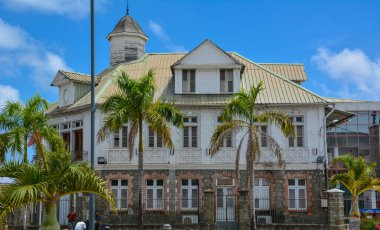 Le Francois, Martinique - 18 Eylül 2018: Hotel de Ville, Belediye Binası - mavi gökyüzünün altında beyaz bulutlu eski bir palmiye ağacı. Boşluğu kopyala
