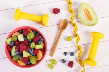 Taze meyve salatası, santimetre ve halter için fitness, spor, diyet, zayıflama, sağlıklı yaşam ve beslenme kavramı