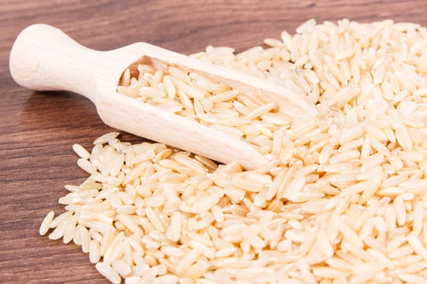 Köy tahtasında ahşap kepçeli kahverengi pirinç yığını, sağlıklı beslenme kavramı.