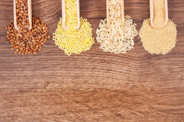 Çeşitli kabuğu çıkarılmış tane, kahverengi pirinç ve rustik masa, sağlıklı, gluten ücretsiz gıda ve beslenme, metin veya yazıt için kopya alanı kavramı üzerinde kepçe ile quinoa tohumları