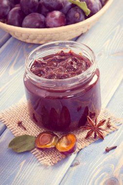 Vintage Fotoğraf, taze ev yapımı erik reçeli veya cam kavanoz, baharatlar ve hasır sepet içinde geçmiş, sağlıklı tatlı tatlı kavramı içinde olgunlaşmış meyve reçeli