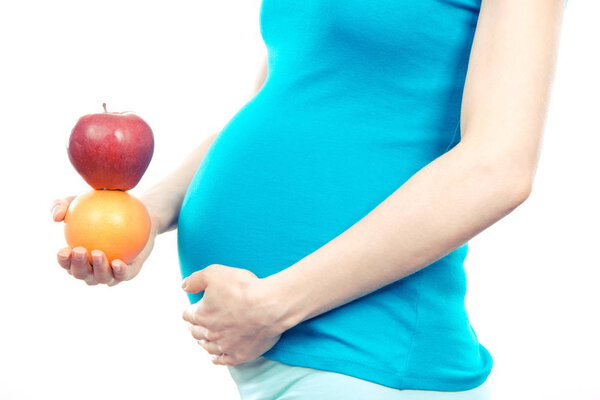 Pregnant woman holding fresh orange and apple, healthy food and nutrition during pregnancy, expecting for newborn
