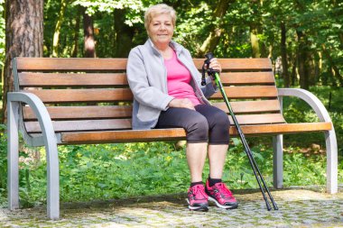 Bankta oturan ve yürüyüşü, temiz havada yaşlılık kavramı üzerinde sağlıklı sportif yaşam sonra dinlenme yaşlı kadın kıdemli