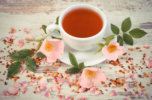 Vintage Fotoğraf, yabani gül, taze çiçek açan çiçekler ile sıcak çay ve çay tahıl rustik yönetim kurulu ile kurutulmuş yaprakları kupa