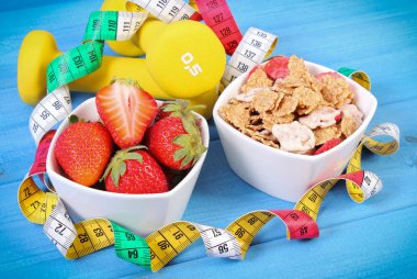 Buğday ve çavdar pul, fitness ve şerit metre, zayıflama, kavramı dumbbells ile taze çilek sportif, sağlıklı yaşam tarzı