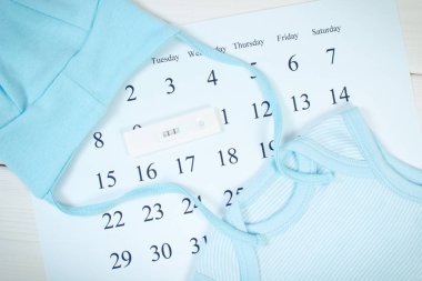 Hamilelik testi pozitif sonuç ve yenidoğan için mavi giyim üzerine takvim, Aile uzanan ve bebek için bekliyor kavramı ile