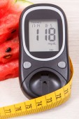 Glükométer ellenőrzésére cukorszint, adag lédús görögdinnye és centiméter, koncepció a cukorbetegség, egészséges táplálkozás és sportos életmód