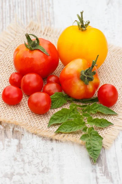 Färska Tomater Med Gröna Blad Jute Duk Gamla Vita Träbord — Stockfoto