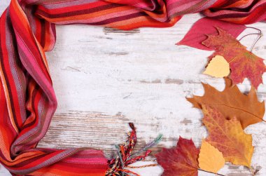 Kadınca yün şal ve sonbahar yaprakları, sıcak giysiler için sonbahar ya da kış, eski rustik ahşap arka plan çerçevesinde