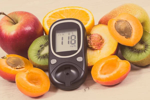 Glucose meter with result of measurement sugar level and fresh nutritious fruits as healthy dessert for diabetics