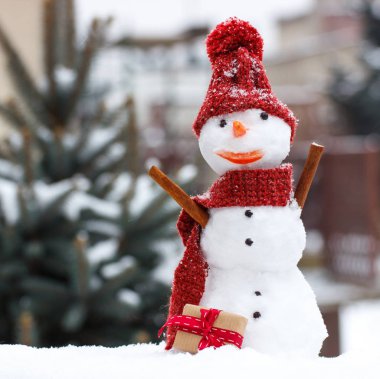 Eşarp ve iğne yapraklı ağaç arka plan üzerinde Noel ya da Sevgililer günü için hediye kap komik kardan adam kar kaplı