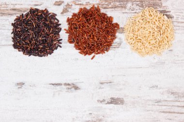 Kahverengi, siyah ve kırmızı pirinç, kavramı sağlıklı, gluten ücretsiz gıda ve beslenme, kopya alanı metin eski rustik tahtada için yığın