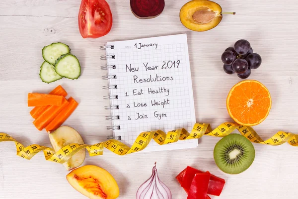 Natural fruits and vegetables with tape measure and new year resolutions of healthy, sporty lifestyles written in notepad