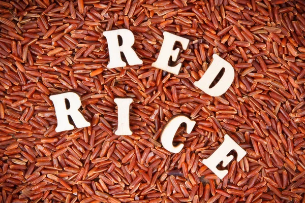 Heap of red rice with inscription as background, concept of healthy, gluten free food and nutrition