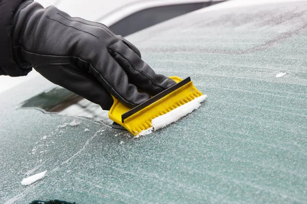 拿着手套拿着黄色刮刀 从车窗上除冰或雪 运输中冬季问题的概念 — 图库照片