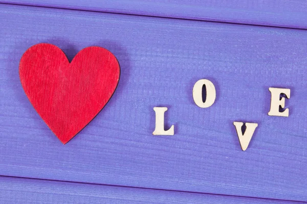 红色的木心与文字爱在紫色的板作为情人节的标志 — 图库照片