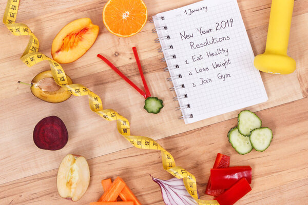 Цели на новый 2019 год записаны в блокноте и свежих спелых фруктах с овощами в виде часов
