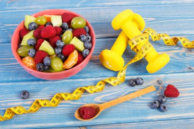 Mezura, dambıl kullanarak fitness ve taze hazırlanmış meyve salatası, spor, diyet, zayıflama, sağlıklı yaşam ve beslenme kavramı için