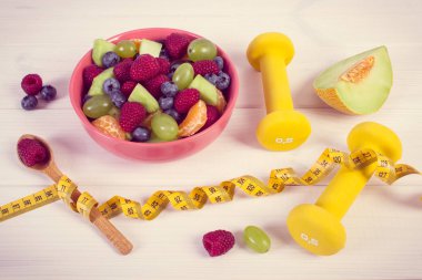 Vintage Fotoğraf, taze meyve salatası, mezura ve halter hazırlanmış fitness içinde kullanma, spor, diyet, zayıflama, sağlıklı yaşam ve beslenme kavramı için