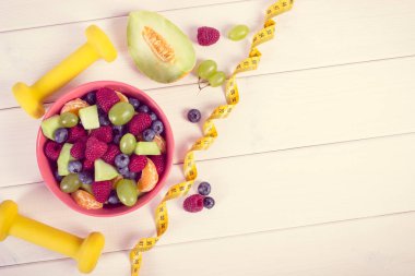 Taze meyve salatası, mezura ve halter hazırlanmış fitness içinde kullanma, spor, diyet, zayıflama, sağlıklı yaşam ve beslenme konsepti için