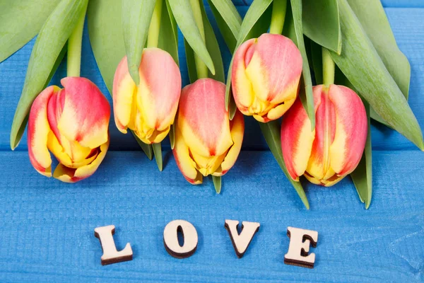Word love and fresh tulips as surprise for Valentines Day, birthday or other occasions