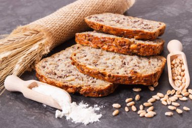 Kahvaltı için bir somun taze kepekli ekmek, pişirmek için malzemeler ve çavdar veya buğday taneleri.