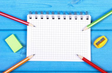 Renkli boya kalemi, kalemtıraş, silgi ve Not defteri başa okul kavramı, mavi kurullarında notlarda metin veya yazıt için yer