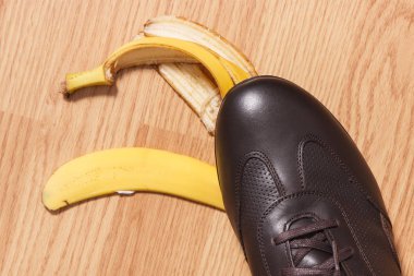 Muz kabuğuna basmadan önce deri kahverengi ayakkabılı ayak.