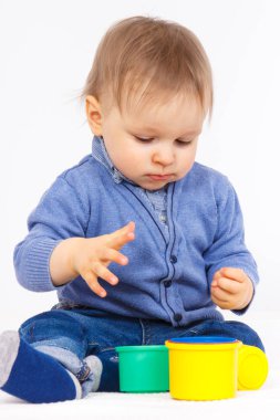 Küçük erkek bebek plastik renkli bardaklarla oynuyor ve öğreniyor. Çocuk gelişimi kavramı.