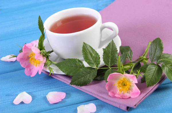 Kopje thee en wild rose bloem op planken — Stockfoto