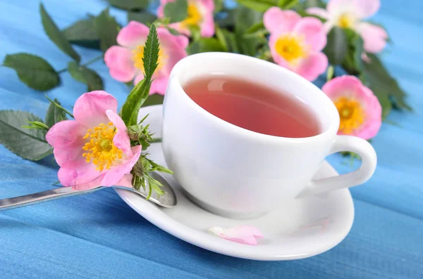 Kopje warme thee en wild rose bloem op planken — Stockfoto