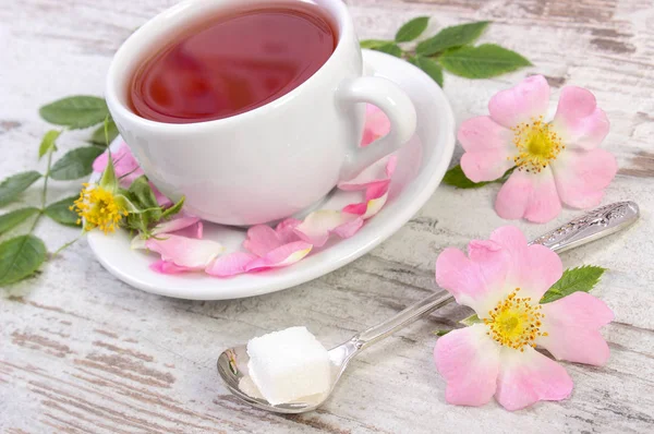 Xícara de chá e flor de rosa selvagem na placa velha — Fotografia de Stock