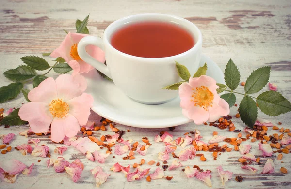Tasse Tee mit Wildrosenblume auf alter rustikaler Planke — Stockfoto
