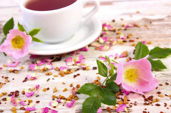 Wild rose bloem en kopje thee op oude bord — Stockfoto